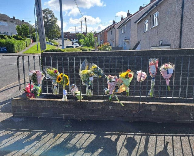 Flower bouquets tied to metal railings in a street 