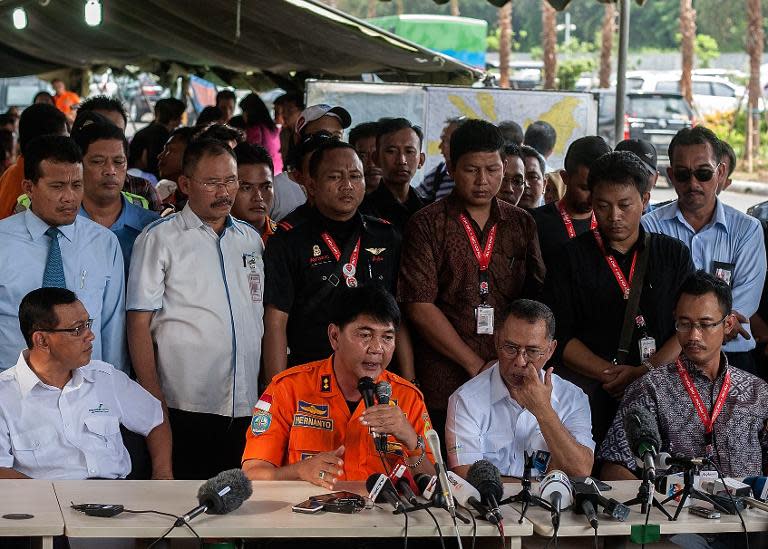 Sunu Widiatmoko (R), the president of Indonesia-AirAsia, listens as Surabaya search and rescue chief Hernanto (2nd L) speaks during a press conference outside the crisis-centre set up at Juanda International Airport in Surabaya