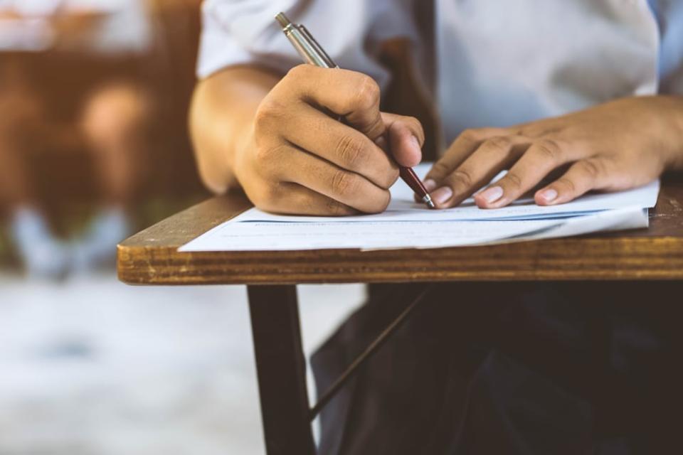 Closeup to hand of student  holding pen and taking exam in classroom with stress for education test .; Shutterstock ID 773969326