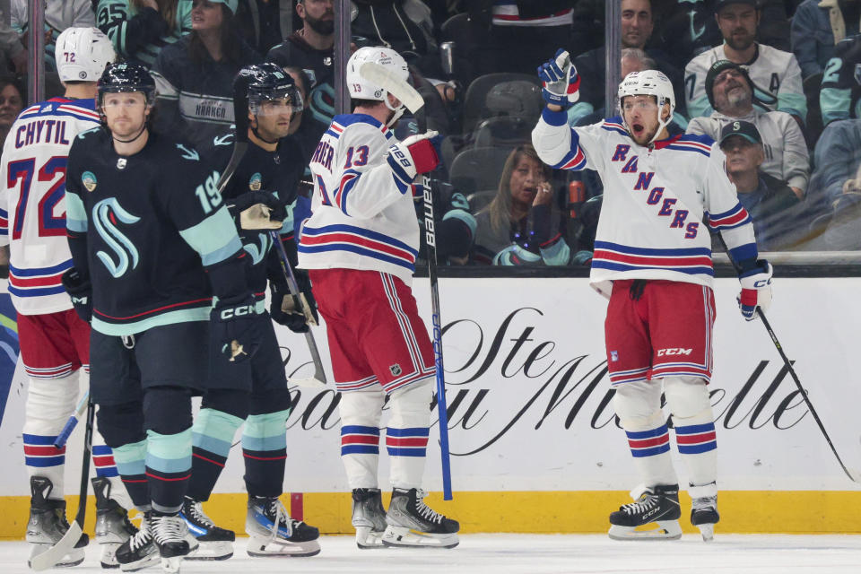 New York Rangers left wing Artemi Panarin, right, celebrates with left wing Alexis Lafreniere (13) after scoring as Seattle Kraken left wing Jared McCann (19) skates away during the first period of an NHL hockey game Saturday, Oct. 21, 2023, in Seattle. (AP Photo/Jason Redmond)