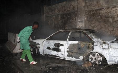 A firefighter looks at a destroyed car at the scene of an explosion outside the Jazira hotel in Mogadishu, January 1, 2014. REUTERS/Feisal Omar