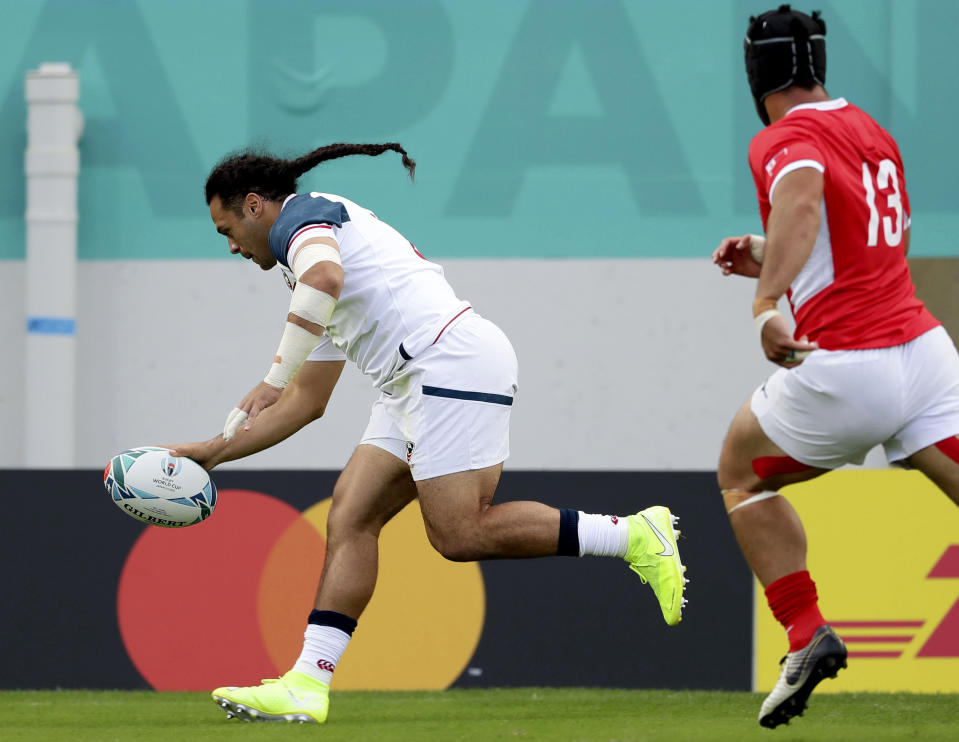 United States' Mike Te'o scores a try as Tonga's Malietoa Hingano, right, watches during the Rugby World Cup Pool C game at Hanazono Rugby Stadium between USA and Tonga in Osaka, Japan, Sunday, Oct. 13, 2019. (Kyodo News via AP)