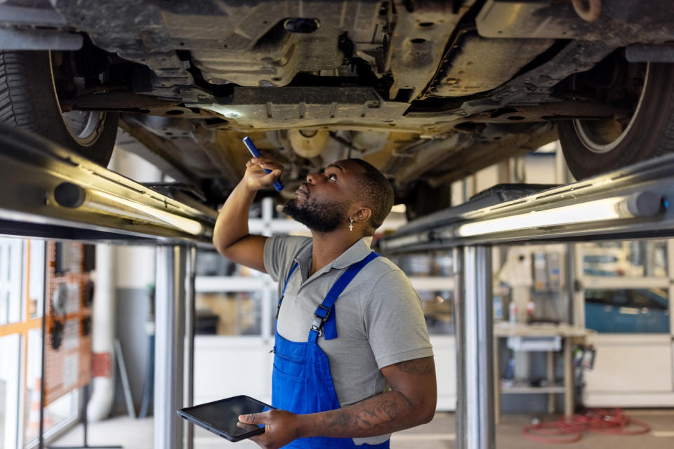 mechanic looking under a car