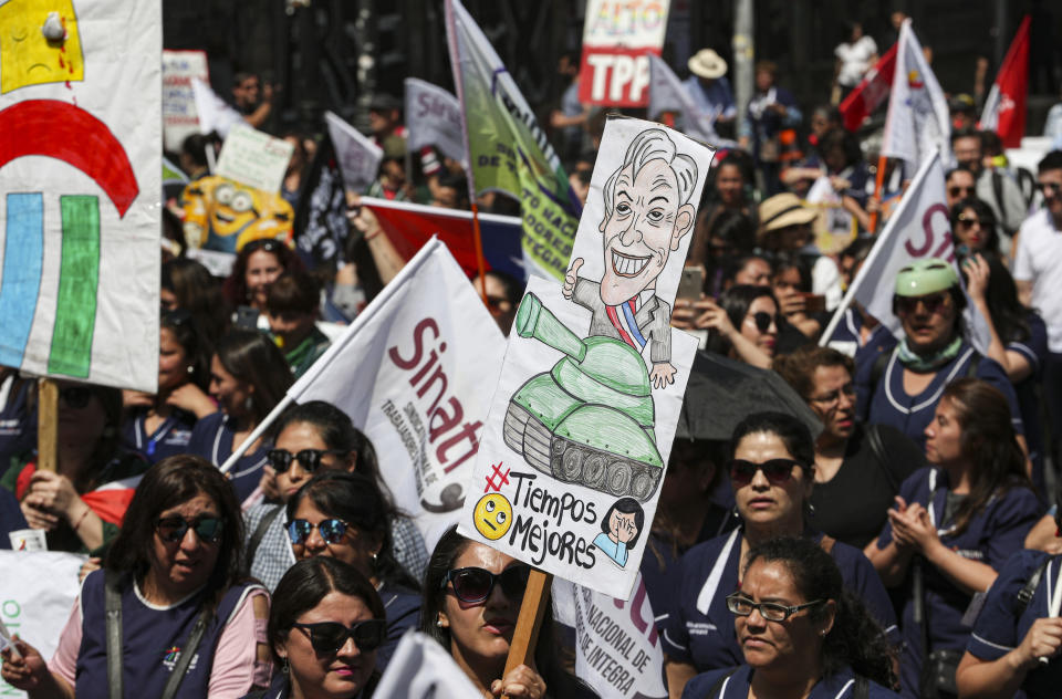 An anti-government demonstrator holds a sign depicting Chile's President Sebastian Pinera during a march near to La Moneda presidential palace in Santiago, Chile, Tuesday, Nov. 12, 2019. Students in Chile began protesting nearly a month ago over a subway fare hike. The demonstrations have morphed into a massive protest movement demanding improvements in basic services and benefits, including pensions, health, and education. (AP Photo/Esteban Felix)