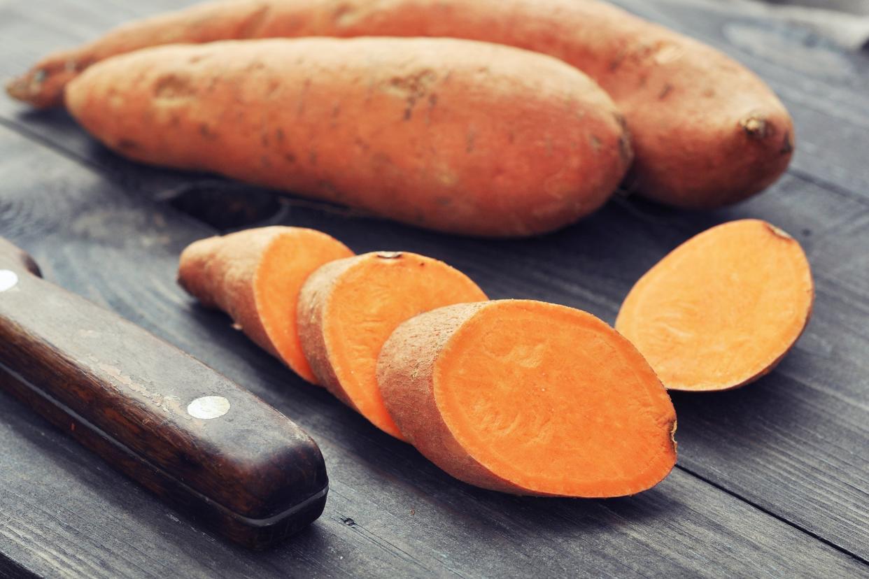 raw sweet potatoes on wooden background