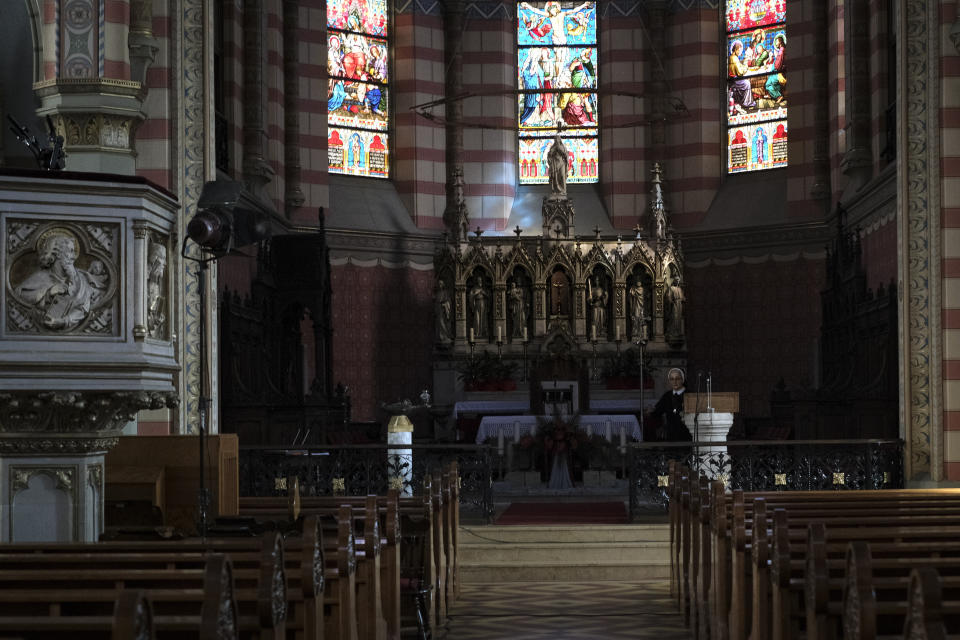 In this Thursday, April 9, 2020 photo, a nun walks inside the Sacred Heart Cathedral in Sarajevo, Bosnia, deserted due to the national lockdown the authorities have imposed attempting to limit the spread of the new coronavirus. (AP Photo/Kemal Softic)
