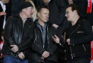 Members of the U2 band, from L-R, the Edge, Larry Mullen and Bono, are seen in the public ahead of the Champions League round of 16 second leg match where AS Monaco plays Arsenal at the Louis II Stadium in Monaco, March 17, 2015. REUTERS/Eric Gaillard (MONACO - Tags: SPORT SOCCER ENTERTAINMENT)