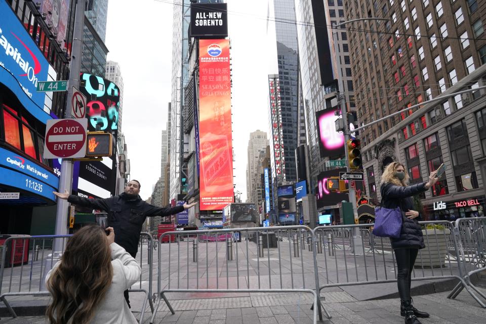 People pose for photographs while wearing protective masks during the coronavirus pandemic in Times Square Thursday, Dec. 31, 2020, in New York. (AP Photo/Frank Franklin II)