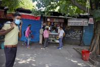 Indians stand outside a local snack shop during extended lockdown in New Delhi, India, Monday, May 18, 2020. India has recorded its biggest single-day surge in new cases of coronavirus. The surge in infections comes a day after the federal government extended a nationwide lockdown to May 31 but eased some restrictions to restore economic activity and gave states more control in deciding the nature of the lockdown. (AP Photo/Manish Swarup)