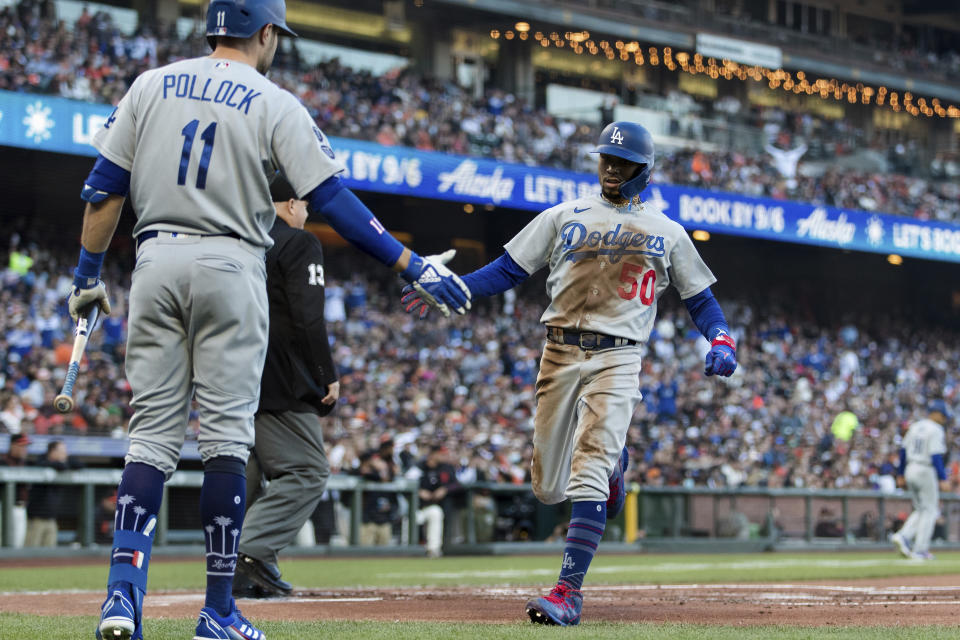 Los Angeles Dodgers' AJ Pollock (11) congratulates Mookie Betts (50) after he scored against the San Francisco Giants in the first inning of a baseball game in San Francisco, Saturday, Sept. 4, 2021. (AP Photo/John Hefti)