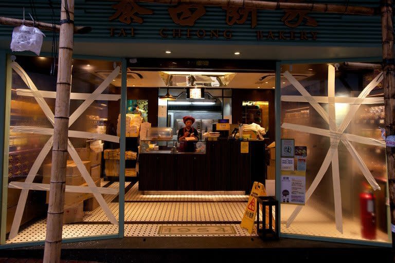 A woman stands at the counter of a Hong Kong bakery which has tape on its windows to protect them from strong winds, on September 23, 2013. Typhoon Usagi killed at least 25 people after crashing ashore in southern China, throwing the region's transport systems into chaos and leaving tens of thousands of airline passengers stranded in Hong Kong on Monday