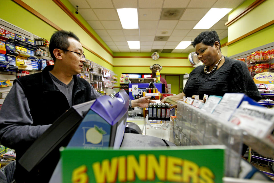 Benita Lewis, 41, of Atlanta, right, buys a Powerball lottery ticket from store worker Bryant Kim, at a convenience store, Wednesday, Nov. 28, 2012, in Atlanta. "I did feel nervous buying it like I could be the one," says Lewis. "I'm going to retire and pay off all my family's debt, immediate family, I got to that back, immediate family's debt." (AP Photo/David Goldman)