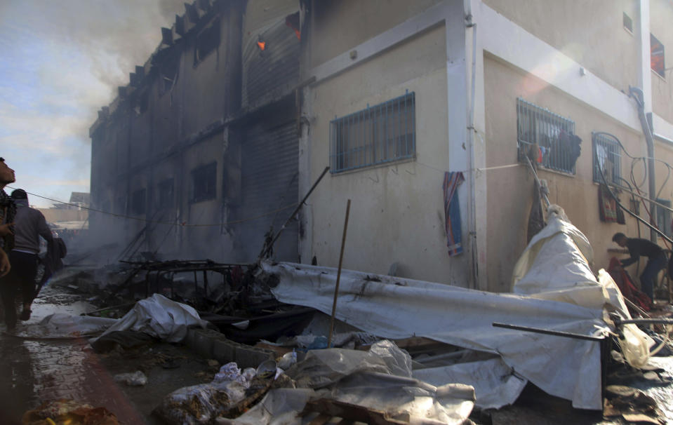 Palestinians try to extinguish a fire at a building of an UNRWA vocational training center which displaced people use as a shelter, after being targeted by Israeli tank shill in Khan Younis, southern Gaza Strip, Wednesday, Jan. 24, 2024. (AP Photo/Ramez Habboub)