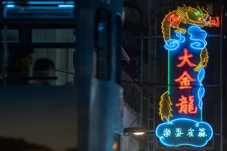 A tram passes a neon sign for 'Golden Dragon Mahjong' in Hong Kong