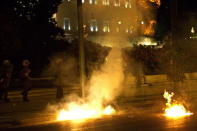 Riot police stand next to flames from exploded petrol bombs thrown by a small group of anti-establishment demonstrators in front of the parliament in Athens, Greece July 22, 2015. REUTERS/Ronen Zvulun