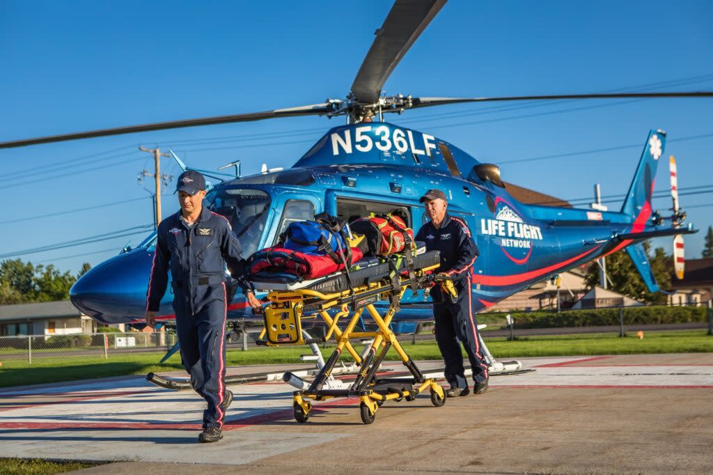 Two paramedics move a patient on a gurney from a helicopter