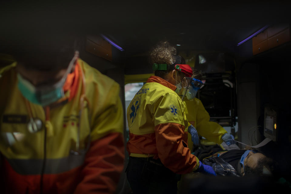 Paramedics tend to a patient who doesn't have COVID-19 inside an ambulance in Barcelona, Spain, April 6, 2020. Medical crews have been doing extra duty during the coronavirus pandemic, checking on patients who are positive and not. (AP Photo/Emilio Morenatti)