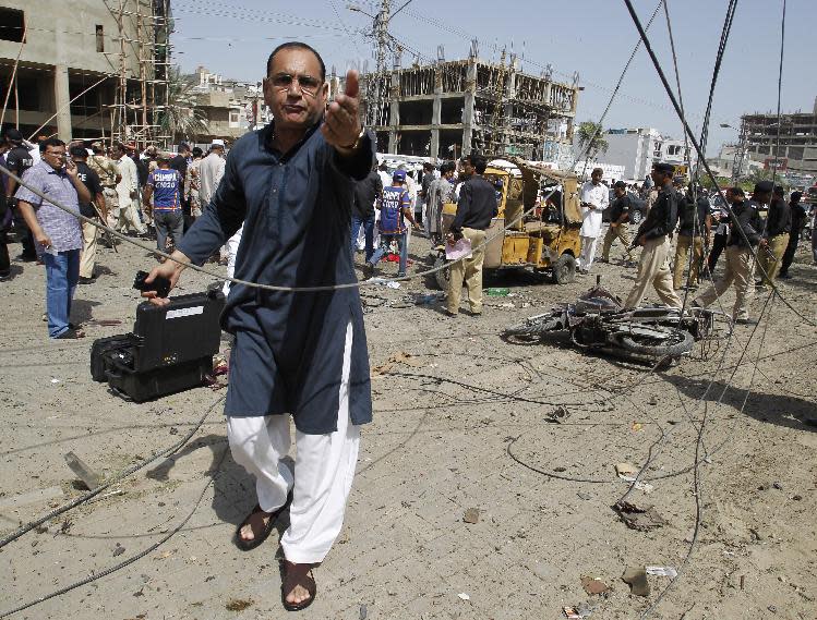 A Pakistani security official stops photographers at the site of an explosion in Karachi, Pakistan, Friday, April 25, 2014. A powerful bomb exploded Friday in an upscale residential area of southern Pakistan, killing several people and wounding others, authorities said. The attack took place in the neighborhood of Clifton in Karachi, the capital of southern Sindh province, senior police officer Abdul Khaliq Sheikh said. The bomb badly damaged several vehicles and a nearby multi-story building. (AP Photo/Fareed Khan)