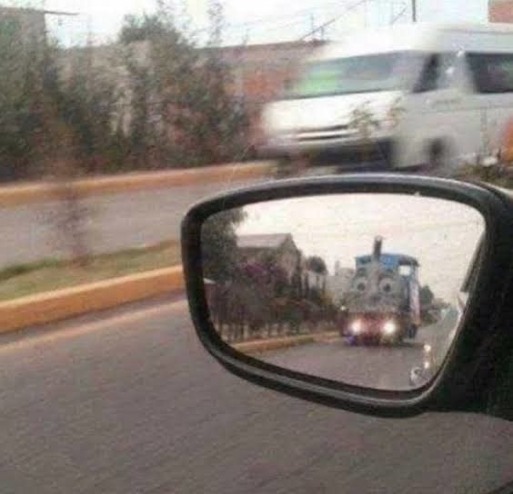 Thomas the Tank Engine driving up behind someone's car, as seen from the side view mirror