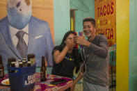 Migrants Aura Berrios and Josue Madariaga make a video call to a fellow migrant who walked with them in the recent migrant caravan, from a bar in Monterrey, Nuevo Leon state, Mexico, Nov. 28, 2021, after obtaining the visitor's card for humanitarian reasons, which allows them stay and move legally in Mexico for one year. (AP Photo/Felix Marquez)