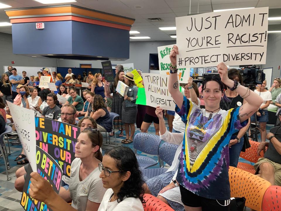 Marissa Paolo, a Turpin High School alumnus, stood with her sign throughout a standing-room-only Forest Hills School Board meeting at Nagel Middle School on June 29, 2022.