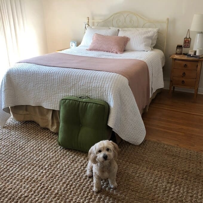 reviewer image of the white quilt set on their bed with their dog in front of the bed