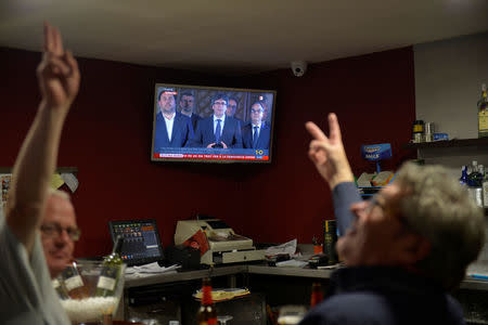Two men make victory sign while watching a televised speech by Catalan president Carles Puigdemont in a bar following the banned October 1 independence referendum, in the Catalan town of Vic, Spain, October 1, 2017. REUTERS/Vincent West