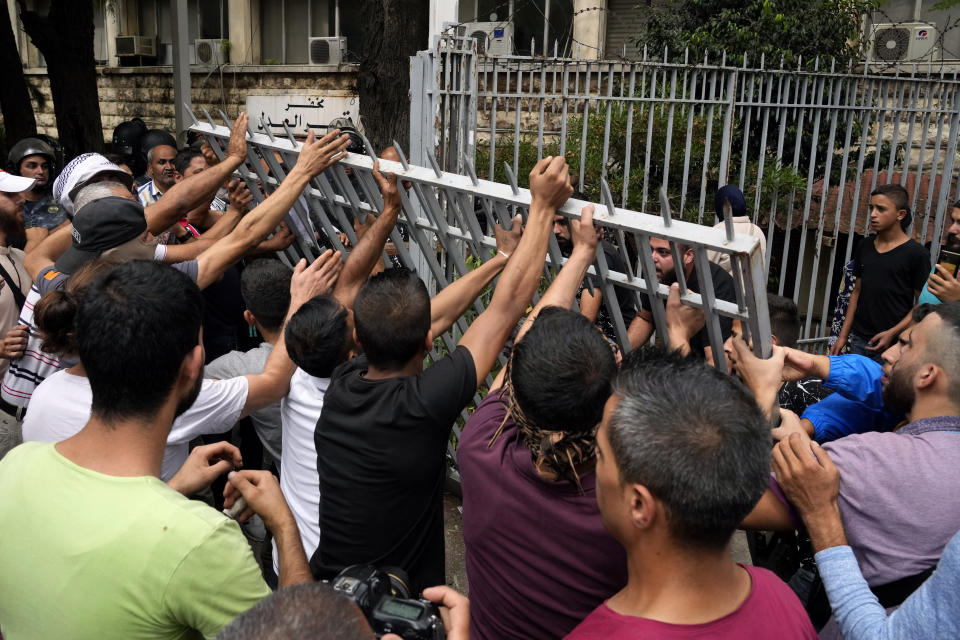 Protesters remove a gate to the Justice Palace during a demonstration demanding the release of two people arrested last week during a bank robbery, in Beirut, Lebanon, Monday, Sept. 19, 2022. Anger with local lenders who have been imposing informal capital controls including limits on ATM withdrawals for nearly three years increased in recent weeks, with some depositors storming bank branches and taking their trapped savings by force. (AP Photo/Bilal Hussein)