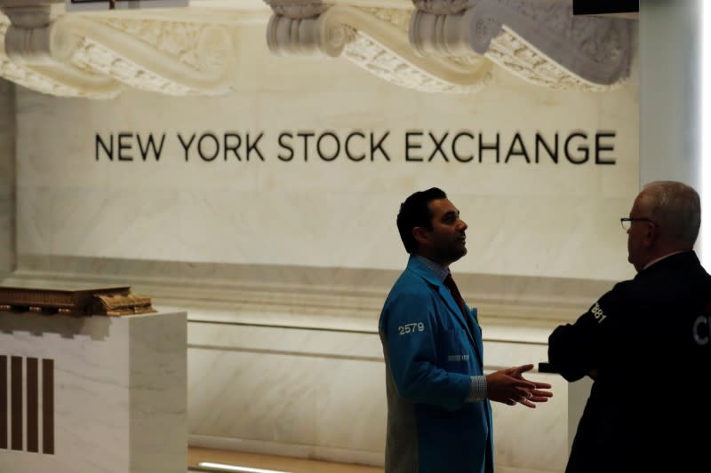 Traders talk as they work on the floor of the New York Stock Exchange (NYSE) on the last work day before its closure due to the coronavirus disease (COVID-19) outbreak in New York