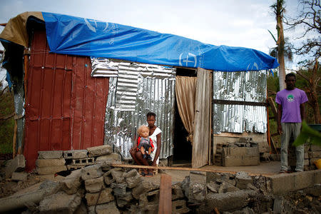 Eric Dominique (R), 26, poses for a photograph with his wife Mickerlange Pierre, 25, and their one-year-old son Jevens, in front of their partially rebuilt house after Hurricane Matthew hit Jeremie, Haiti, October 20, 2016. "My house was completely destroyed during the hurricane, no one died but we lost everything; clothes, my son's medical reports, his medicines, money, everything. I built this small place to live with my baby and my wife. This is my new house, but our situation is very bad. I'm concerned about my baby, we really need help," said Dominique. REUTERS/Carlos Garcia Rawlins