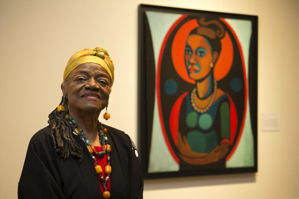 Artist Faith Ringgold poses for a portrait in front of a painted self-portrait during a press preview of her exhibition, "American People, Black Light: Faith Ringgold’s Paintings of the 1960s" at the National Museum of Women in the Arts in Washington on Wednesday, June 19, 2013. Ringgold explains her "confrontational art" _ vivid paintings whose themes of race, gender, class and civil rights were so intense that for years, no one would buy them. "I didn’t want people to be able to look, and look away, because a lot of people do that with art," Ringgold said. "I want them to look and see. I want to grab their eyes and hold them, because this is America." (AP Photo/Jacquelyn Martin)