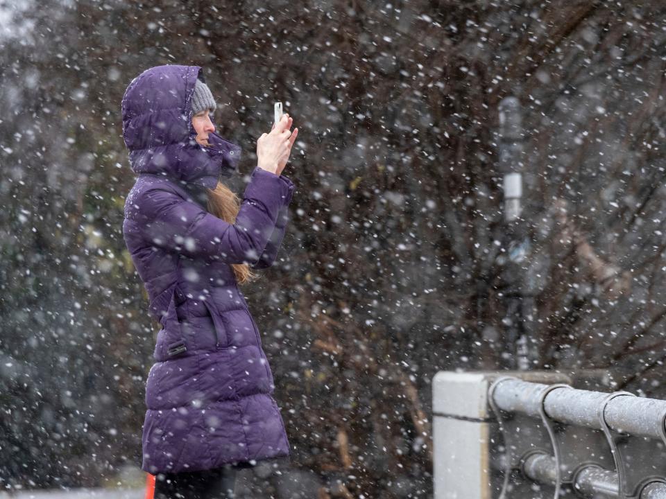 Bridget Step stops for a photo of the snow while watching the snow fall in Atlanta as a winter storm rolls into the area Sunday, Jan. 16, 2022.