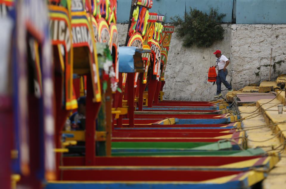 A boat worker carries a life preserver, one of a half dozen that were visible, on to a trajinera, colorful passenger boats typically rented by tourists, families, and groups of young people, in Xochimilco, Mexico City, Friday, Sept. 6, 2019. The usually festive Nativitas pier was subdued and largely empty Friday afternoon, with some boat operators and vendors estimating that business was down by 80% on the first weekend following the drowning death of a youth that was captured on cellphone video and seen widely in Mexico. Borough officials stood on the pier to inform visitors of new regulations that went into effect Friday limiting the consumption of alcohol, prohibiting the use of speakers and instructing visitors to remain seated.(AP Photo/Rebecca Blackwell)