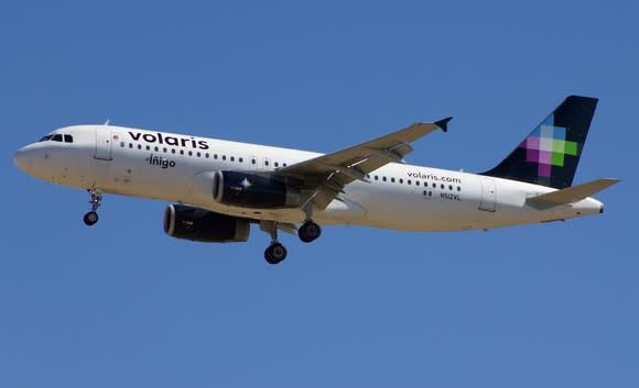 A Volaris airplane in flight under blue skies