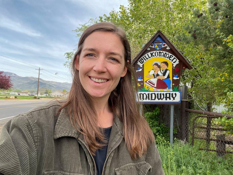 The author in front of the sign welcoming people to Midway, Utah.