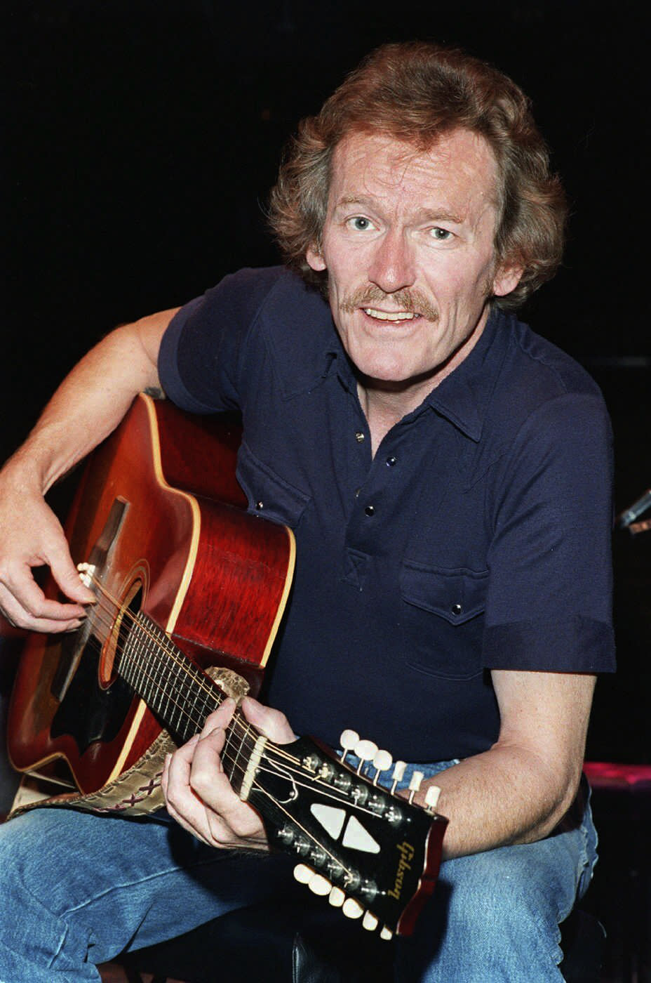 FILE - Singer-songwriter Gordon Lightfoot, strums backstage at the Westbury Music Fair on Sept. 8, 1987, in Westbury, N.Y. Canada's legendary folk singer-songwriter, whose hits include “Early Morning Rain” and “The Wreck of the Edmund Fitzgerald," died on Monday, May 1, 2023, at a Toronto hospital, a representative of his family said. He was 84. (AP Photo/Cyrena Chang, File)