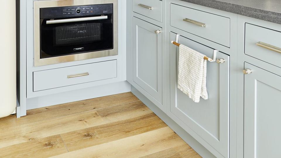 a kitchen with pale blue cabinets, white tile backsplash and white shelving