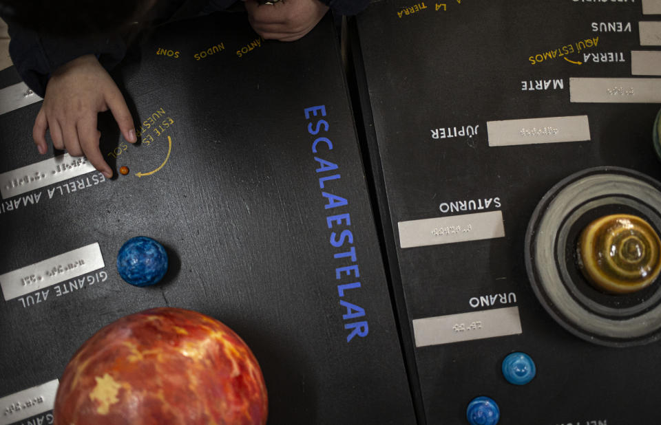 A blind child interacts with a representation of the solar system during sensorial experience with tools created by NASA and Edinburgh University to experience an eclipse, at the Helen Keller school in Santiago, Chile, Tuesday, June 25, 2019. The event comes exactly one week ahead of a total solar eclipse which is set to be fully visible in various South American countries, including Chile. (AP Photo/Esteban Felix)