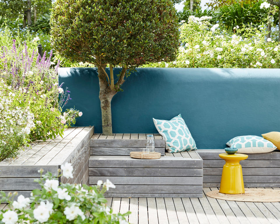 <p> Small garden decking ideas can be so much more than a simple level for you to walk on. You can create raised areas, like these, that can be used for seating and as somewhere to place drinks and nibbles if you are entertaining.&#xA0; </p> <p> They also add interest to the corner of your garden. We love how this decking area is edged with flowers and a painted wall, and utilises soft, washed deck colors that complement the vivid blue of the wall. </p>