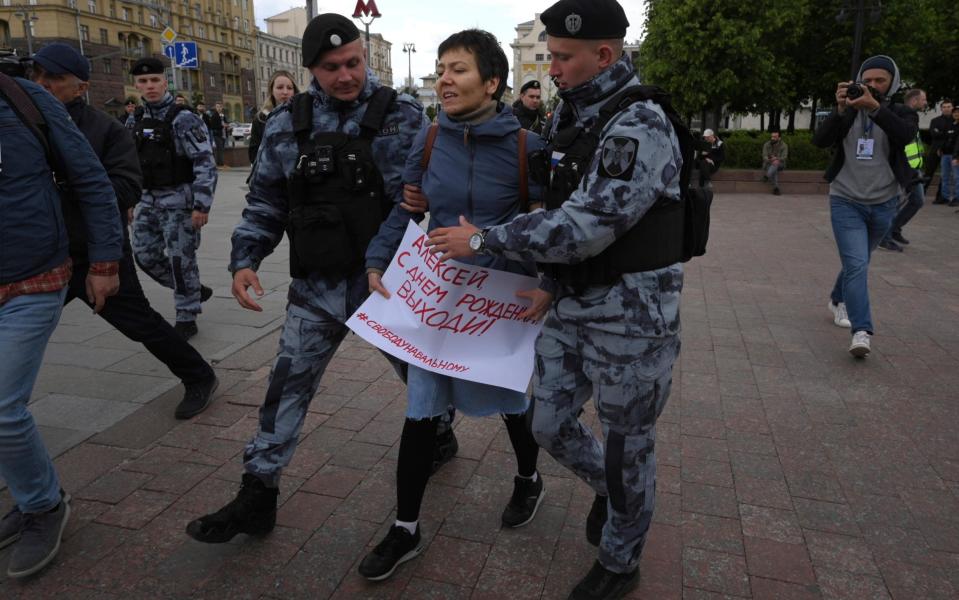 Police officers detain a demonstrator with a poster that reads: "Happy Birthday Alexei (Navalny)" in Moscow - AGP