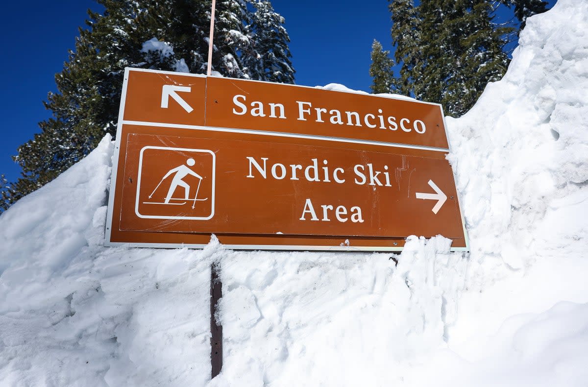 A road sign pointing towards San Francisco and a ski area is partially buried in a snowbank after a series of atmospheric river storms on January 20, 2023 in Yosemite National Park, California (Getty Images)