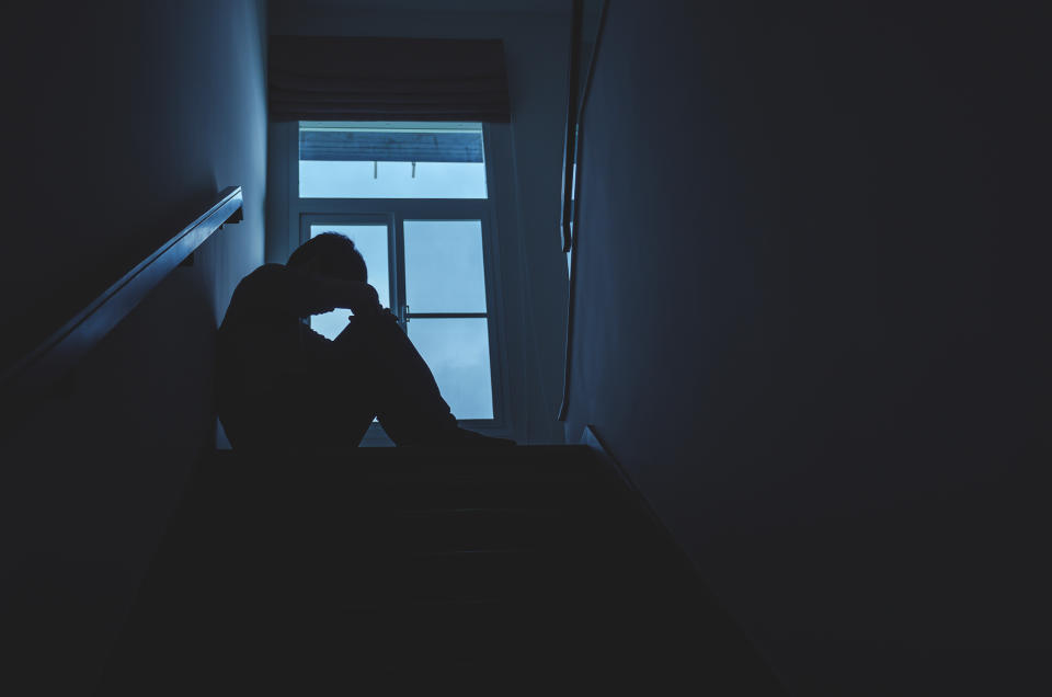 A silhouette of a person is seen at the stop of a flight of stairs. 