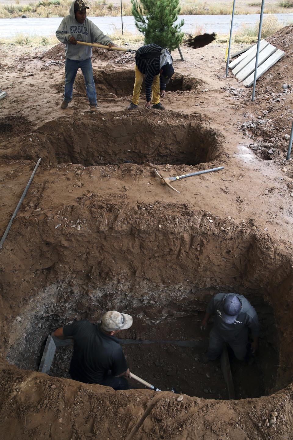 Men dig graves for Rhonita Miller, 30, and four of her young children Krystal and Howard, and twins Titus and Tiana, who were murdered by drug cartel gunmen, before their burial at a cemetery in LeBaron, Chihuahua state, Mexico, Friday, Nov. 8, 2019. A total of three women and six of their children, from the extended LeBaron family, were gunned down in a cartel ambush while traveling along Mexico's Chihuahua and Sonora state border on Monday. (AP Photo/Marco Ugarte)