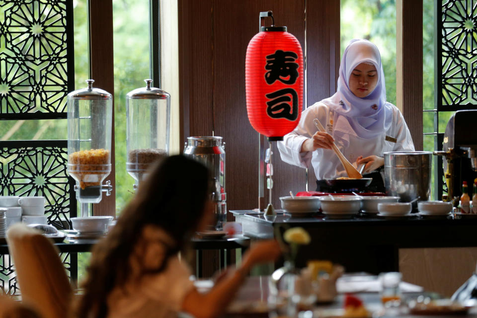 A Muslim employee cooks as a visitor has breakfast at the Al Meroz hotel in Bangkok