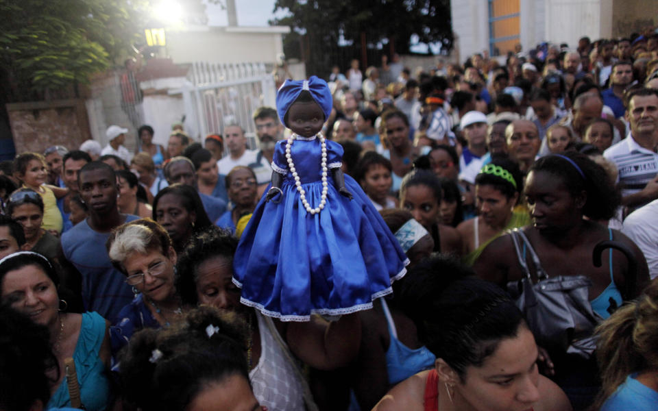 FILE - A woman holds up a doll representing the Virgin of Regla during a procession in her honor in Regla, Cuba, Sept. 7, 2010. The black virgin is honored on the same day as Cuba's patron saint the Virgin of Charity, both of which are also recognized as powerful deities in the African-influenced religion of Santeria. (AP Photo/Javier Galeano, File)