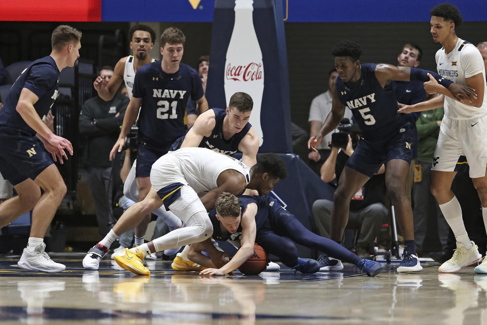 West Virginia forward Mohamed Wague (11) and Navy guard Austin Benigni (1) vie for a loose ball during the first half of an NCAA college basketball game in Morgantown, W.Va., Wednesday, Dec. 7, 2022. (AP Photo/Kathleen Batten)