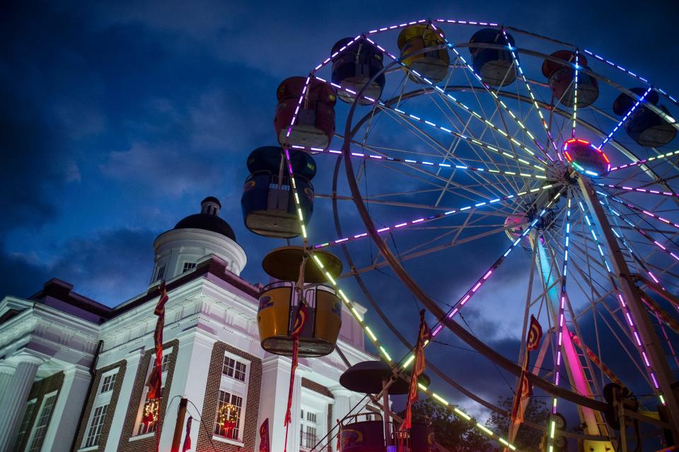 Colorful lights illuminate the Ferris wheel outside of the old Madison County Courthouse at the Canton Christmas Festival in downtown Canton, Friday, Dec. 4, 2020.