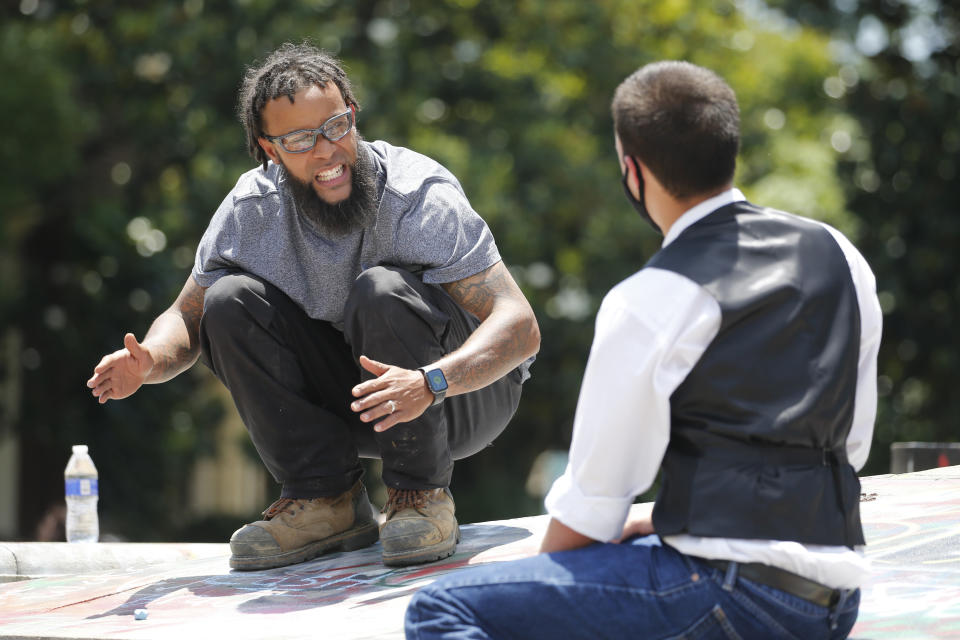 Chazz Woodson, left, and Aidan Aparicio, both from Richmond, talk on the base of the statue of Confederate General Robert E. Lee on Monument Avenue Wednesday June 24, 2020, in Richmond, Va. The statue has become a focal point of protests for the Black Lives Matter movement in the Richmond area. (AP Photo/Steve Helber)