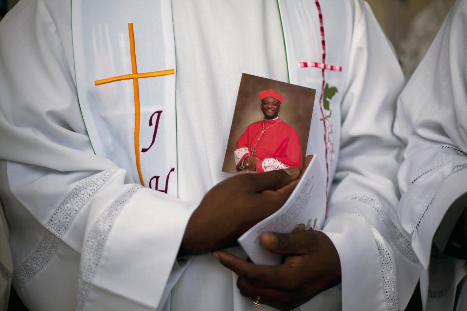 A priest holds a picture of Haiti's first Cardinal Chibly Langlois during a Mass lead by Langlois in Port-au-Prince, Haiti, Sunday March 9, 2014. Langlois reminded Sunday's crowd at the soccer stadium that many would go hungry or wouldn't be able to survive were it not for the kindness of others. (AP Photo/Dieu Nalio Chery)