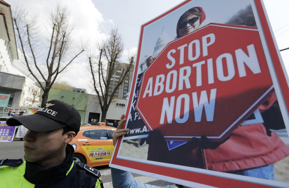 A pro-life demonstrator holds a banner near a police officer during a rally supporting South Korea's anti-abortion regulations outside of the Constitutional Court in Seoul, South Korea, Thursday, April 11, 2019. In a major reversal, South Korea's Constitutional Court on Thursday ordered the easing of the country's decades-long ban on abortions, one of the strictest in the developed world. (AP Photo/Lee Jin-man)